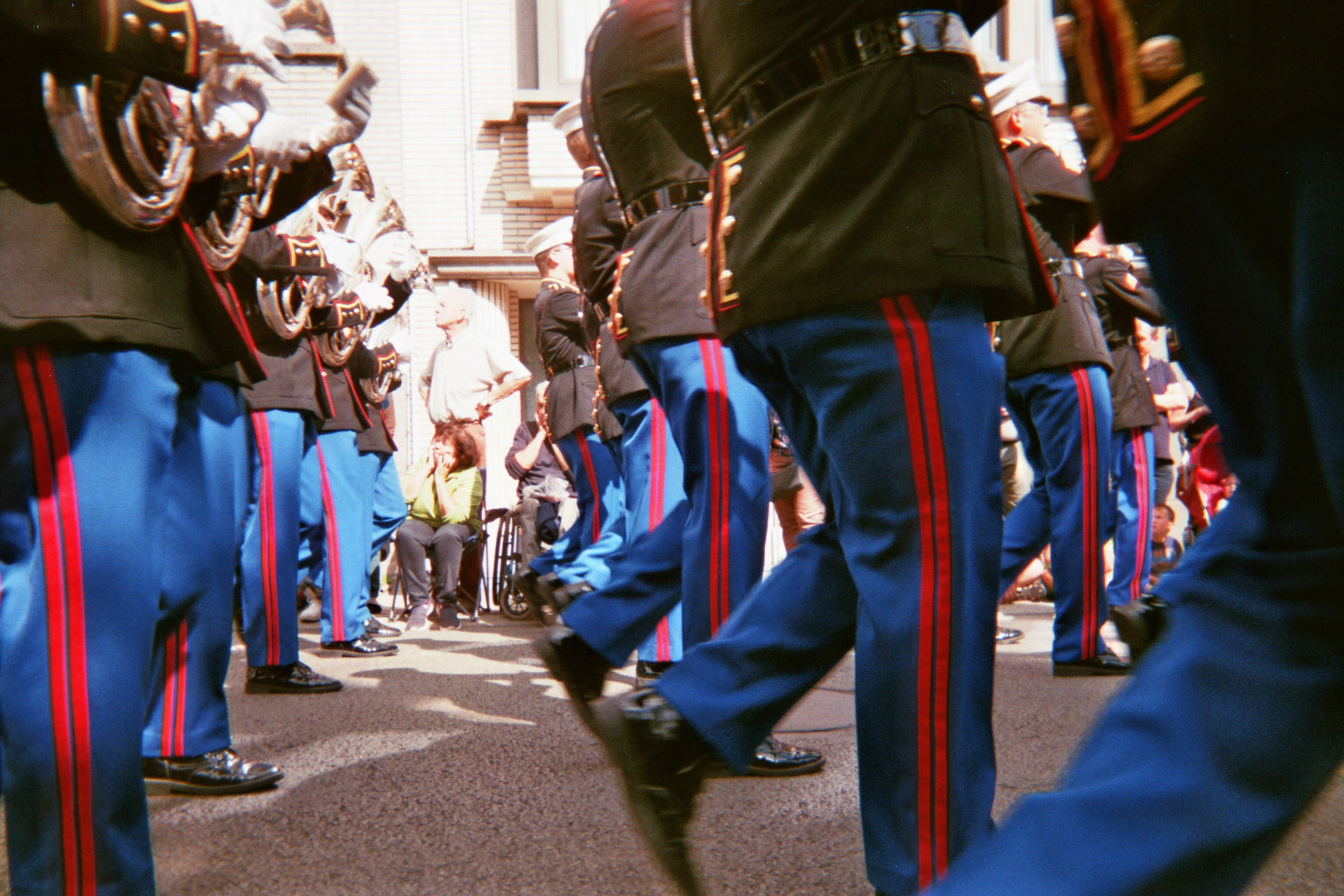 Marching band's legs and feet with blue pants with a red stripe
